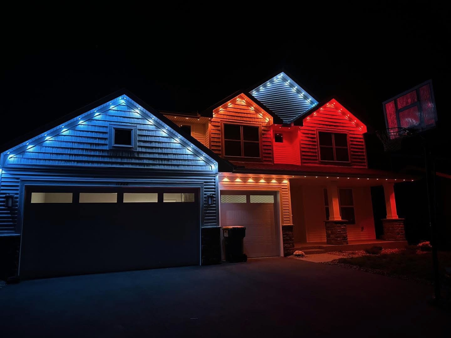 Home roofline lit in blue, white, and red permanent LED lighting at night