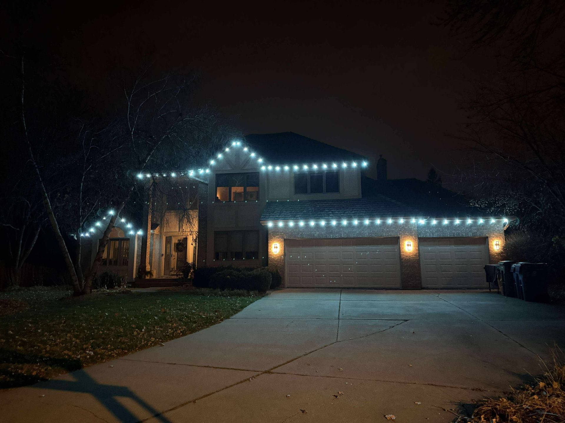Large home outlined in cool white permanent LED lighting at night