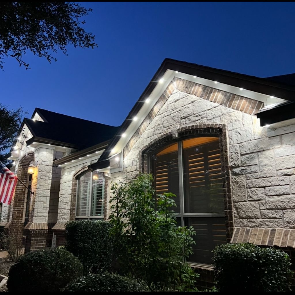 Stone Texas home with crisp white permanent LED roofline lighting at dusk